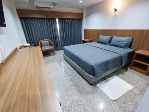 a bedroom with a blue bed and a chair at New Siya in Maha Sarakham