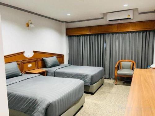 a hotel room with two beds and a chair at New Siya in Maha Sarakham