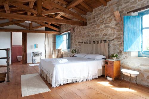 a bedroom with a white bed and a stone wall at Domu Antiga in Gergei
