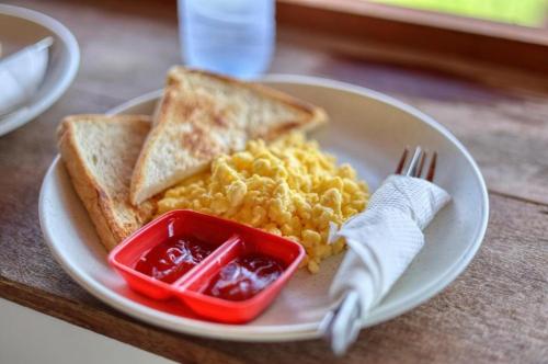 a plate with scrambled eggs and toast on a table at D Sebuluh Guest House in batumadeg