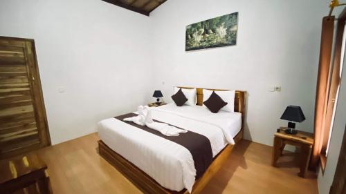 a bedroom with a bed with white sheets and pillows at D Sebuluh Guest House in batumadeg