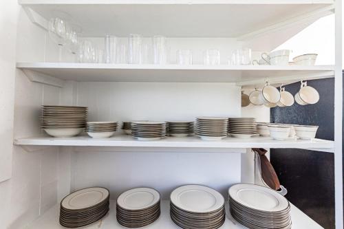 a shelf with plates and bowls and utensils in a kitchen at THE HILO HAVEN - 4Bd2Ba Entire House w AC, BBQ, Firepit in Hilo