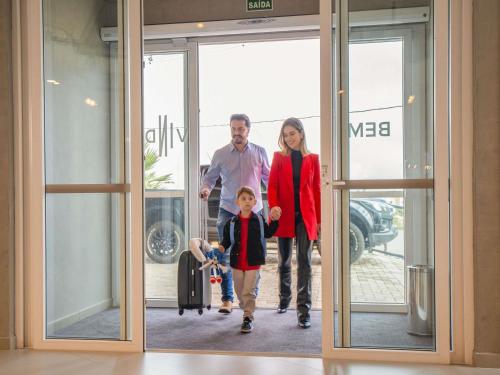 a family walking out of an airport door at ibis Guarapuava in Guarapuava