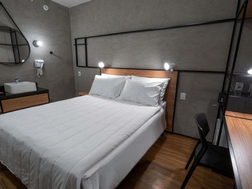 a bedroom with a large white bed and a sink at ibis Guarapuava in Guarapuava