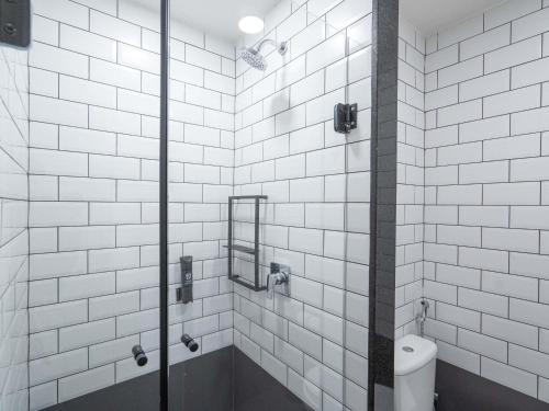 a white tiled bathroom with a shower with a toilet at ibis Guarapuava in Guarapuava