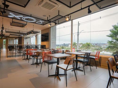 a restaurant with tables and chairs and large windows at ibis Guarapuava in Guarapuava