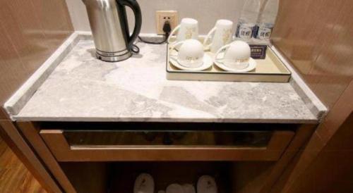 a marble counter top with cups and plates on it at East Queen Hotel (Xi'an Beimen Metro Station) in Xi'an