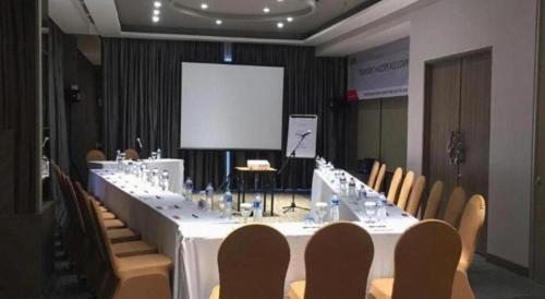 a long table in a room with chairs and a screen at Patra Cirebon Hotel & Convention in Cirebon