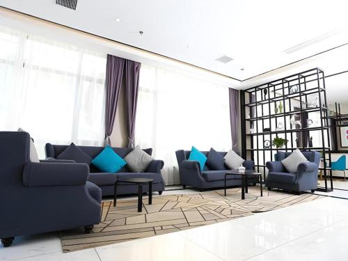 a living room with blue couches and windows at Xana Hotelle·Ji'nan Hi-tech Zone Century Avenue Tangye in Jinan