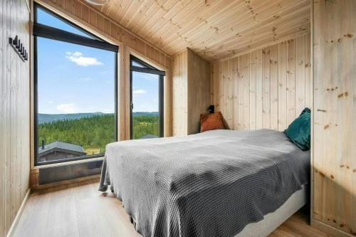 een slaapkamer met een bed en een groot raam bij Mountain Cabin With Panoramic Views In Norefjell in Runn
