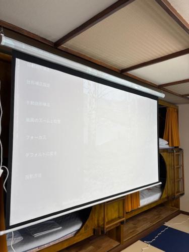 a large projection screen in a room at 新規オープン岩風呂付ゲストハウス織姫 in Fujiyoshida