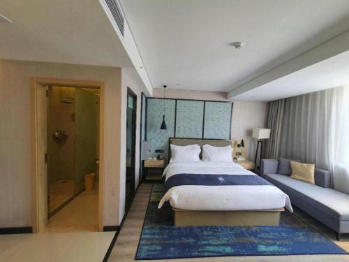 a bedroom with a large bed and a couch at Echarm Hotel Yingshang High-speed Railway Station Wuzhou Wanhui Plaza in Fuyang
