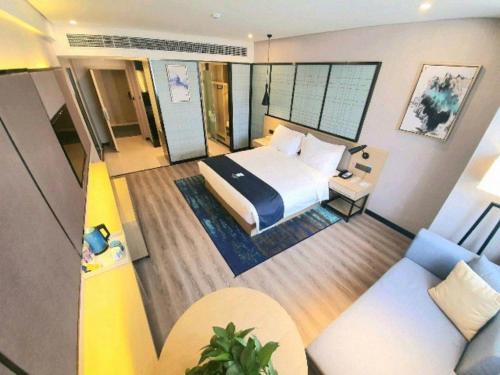 a hotel room with a bed and a couch at Echarm Hotel Yingshang High-speed Railway Station Wuzhou Wanhui Plaza in Fuyang