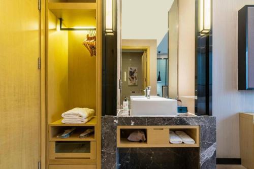 a bathroom with a sink and a mirror at Echarm Hotel Yingshang High-speed Railway Station Wuzhou Wanhui Plaza in Fuyang