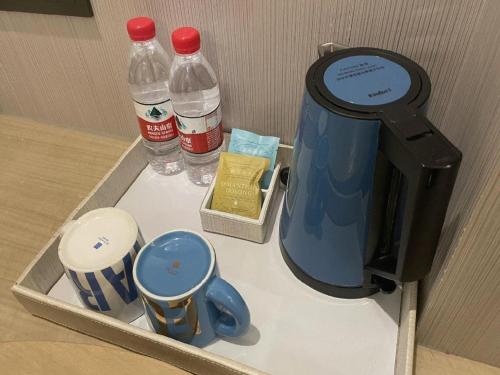 a box with a jug and cups and water bottles at Echarm Hotel Yingshang High-speed Railway Station Wuzhou Wanhui Plaza in Fuyang