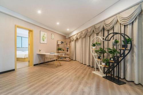 a living room with a table and plants in it at Echarm Hotel Yingshang High-speed Railway Station Wuzhou Wanhui Plaza in Fuyang
