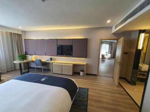 a hotel room with a large bed and a desk at Echarm Hotel Yingshang High-speed Railway Station Wuzhou Wanhui Plaza in Fuyang