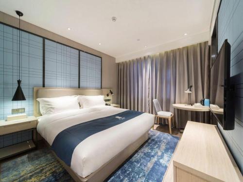 a hotel room with a large bed and a desk at Echarm Hotel Yingshang High-speed Railway Station Wuzhou Wanhui Plaza in Fuyang