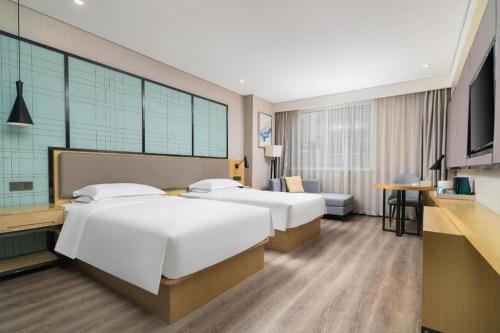 a hotel room with two beds and a television at Echarm Hotel Yingshang High-speed Railway Station Wuzhou Wanhui Plaza in Fuyang