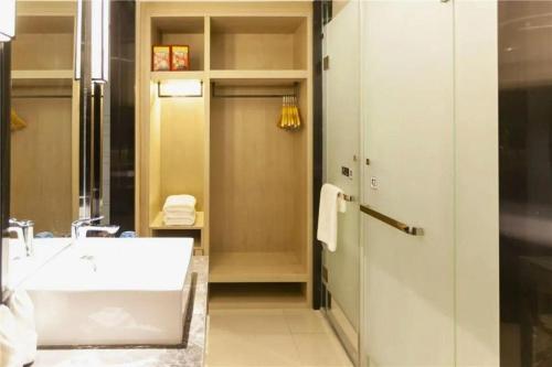 a bathroom with a white tub and a sink at Echarm Hotel Yingshang High-speed Railway Station Wuzhou Wanhui Plaza in Fuyang