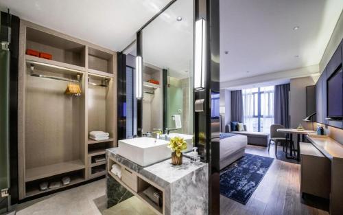 a bathroom with a sink and a room with a couch at Echarm Hotel Yingshang High-speed Railway Station Wuzhou Wanhui Plaza in Fuyang