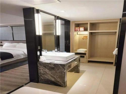 a bathroom with a large sink and a bed at Echarm Hotel Yingshang High-speed Railway Station Wuzhou Wanhui Plaza in Fuyang