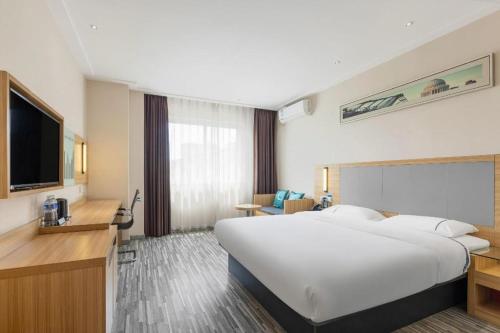 a hotel room with a large white bed and a television at City Comfort Inn Zhanjiang Middle Renmin Avenue Dingsheng Square in Zhanjiang