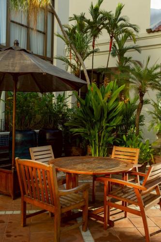 a wooden table and chairs with an umbrella at CS Pattani Hotel in Ban Ru Sa Mi Lae