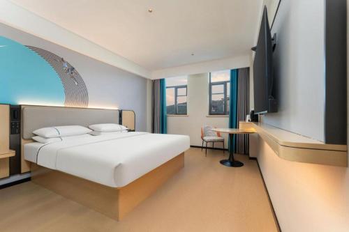a bedroom with a bed and a desk and a tv at City Comfort Inn Shiyan Wudang Mountain in Danjiangkou
