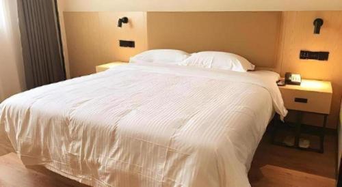 a white bed with white sheets and pillows at GreenTree Inn Express Yingtan Yujiang Railway Station in Yingtan