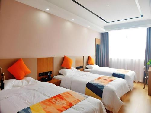 a hotel room with three beds with orange pillows at Shell Hotel Wuhu Jiujiang District Daqiao Town Huashan Road in Wuhu