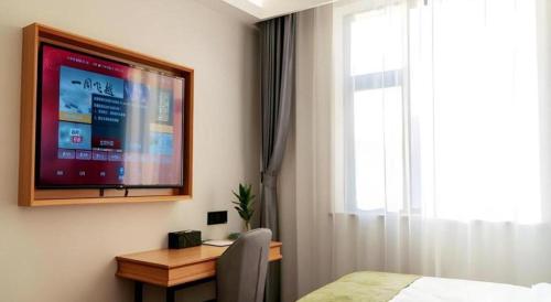 a bedroom with a desk and a tv on the wall at GreenTree Inn Express Datong High-Speed Railway Station Old City Wall in Datong