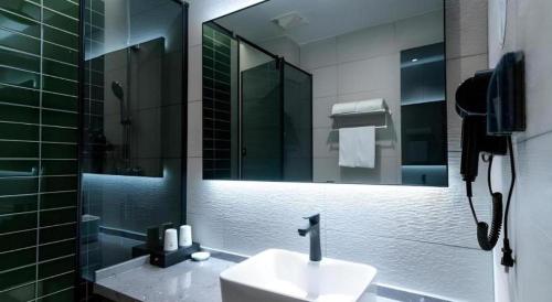 a bathroom with a sink and a shower and a mirror at GreenTree Inn Express Hebei Tangshan Guyan District Xinguang Road in Tangshan