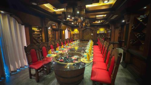 a long dining room with a long table and red chairs at The Signature Hotel Nha Trang in Nha Trang