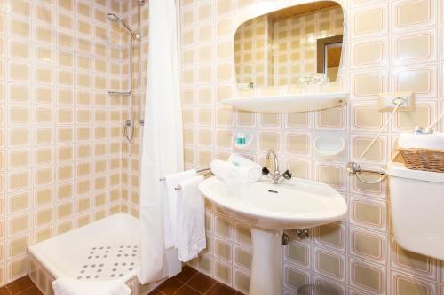 un bagno con lavandino e doccia di Hotel Chalet Olympia a Monguelfo