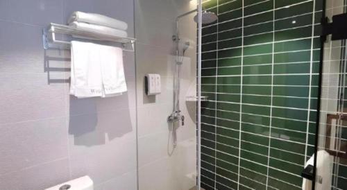 a bathroom with a shower and a green tile wall at GreenTree Inn Express Fuzhou Linchuan District Gandong Auto City in Fuzhou