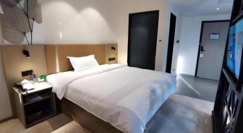 a bedroom with a large white bed and a television at GreenTree Inn Express Fuzhou Linchuan District Gandong Auto City in Fuzhou