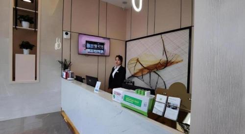 a man is standing behind a counter in a store at GreenTree Inn Express Fuzhou Linchuan District Gandong Auto City in Fuzhou