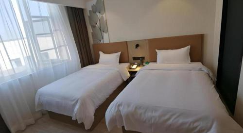 two beds in a hotel room with a window at GreenTree Inn Express Fuzhou Linchuan District Gandong Auto City in Fuzhou