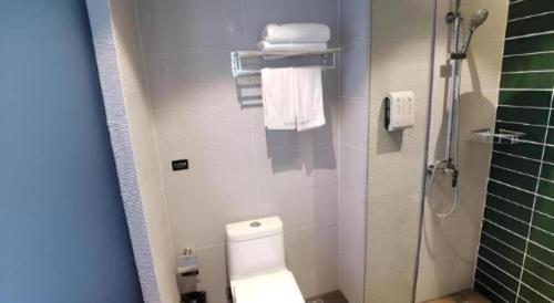 a bathroom with a toilet and a shower with towels at GreenTree Inn Express Fuzhou Linchuan District Gandong Auto City in Fuzhou