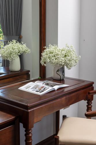 a wooden table with two vases of flowers on it at Tam Coc Orchid Hotel & Spa in Ninh Binh