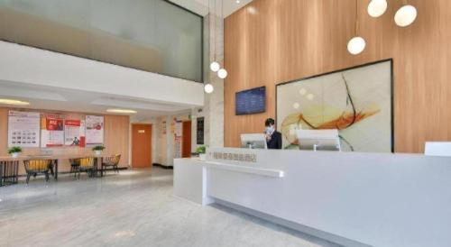 a woman sitting at a desk in an office lobby at Green Tree Inn Express Zhejiang Zhoushan Xincheng Zheda in Zhoushan