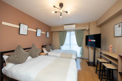 a hotel room with two beds and a flat screen tv at Nakatsu Sakae Manshon in Osaka