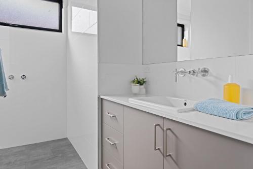 a white bathroom with a sink and a shower at Tea Tree Pool Retreat in Inverloch