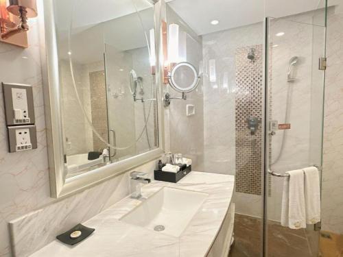 a white bathroom with a sink and a shower at Venus Royal Hotel Guangdong Meizhou Huangjia Mingdian in Meizhou