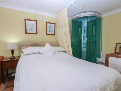 a bedroom with a white bed and a green shower at Maesawel Studio in Harlech