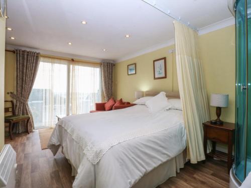a bedroom with a large white bed and windows at Maesawel Studio in Harlech