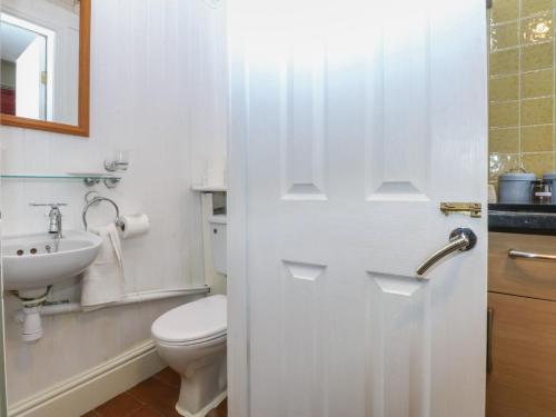 a white bathroom with a toilet and a sink at Maesawel Studio in Harlech
