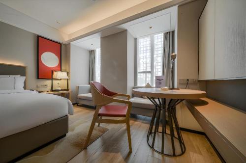 a hotel room with a bed and a desk with a chair at Echeng Hotel Nanning the Mixc Convention in Nanning