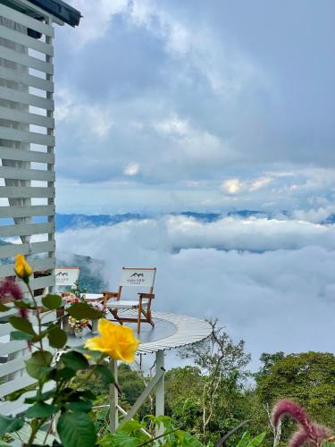 a table and chairs on a balcony with a view of clouds at Naraview at phuchifa in Thoeng